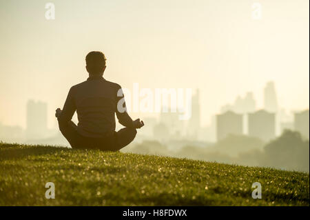 Silhouette eines Mannes sitzen im Lotussitz meditieren vor einem nebligen London Sonnenaufgang auf der Oberseite Primrose Hill Stockfoto