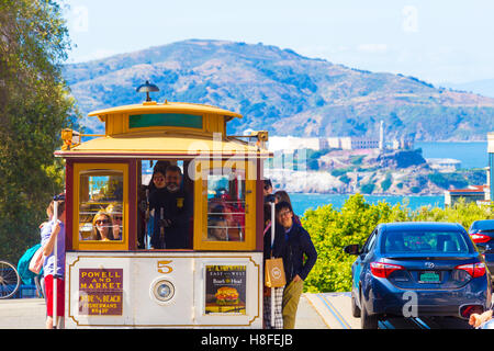 Kultige nahenden Seilbahn voller Touristen an der oberen Spitze der Hyde Street Hill mit Blick auf Alcatraz Insel mit herrlicher natu