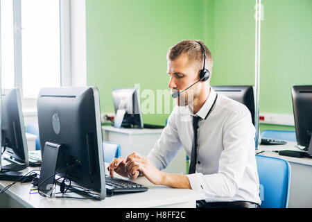 Freudige Agent arbeitet in einem Call-Center mit seinem Kopfhörer Stockfoto