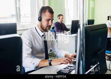 Freudige Agent arbeitet in einem Call-Center mit seinem Kopfhörer Stockfoto