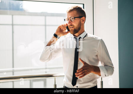 Jungunternehmer am Telefon in der Lobby des Amtes Stockfoto