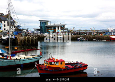 Boote im Hafen von Brixham, Devon, UK. Das Fischrestaurant Drachenköpfe und viele Touristen können im Hintergrund zu sehen. Stockfoto