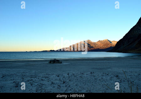 schöne ruhige blaue Wellen schlagen gefrorenen Sandstrand im Spätherbst am Polarkreis mit tiefen Berg und Meer Stockfoto