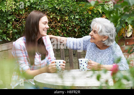 Entspannende Teenager Enkelin mit Oma im Garten Stockfoto