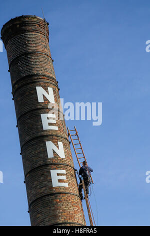 Kirchturm-Buchsen arbeiten auf einem sehr hohen Schornstein an einem sonnigen Tag Stockfoto