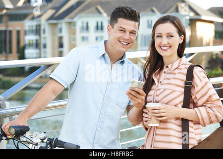 Junges Paar betrachten Telefon unterwegs zur Arbeit im städtischen Umfeld Stockfoto