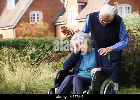 Deprimiert Senior Frau im Rollstuhl geschoben von Ehemann Stockfoto