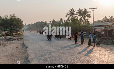 Straße Szene in ländlichen Myanmar in den frühen Morgenstunden. Mönchen Almosen von weiblichen Dorfbewohner erhalten. Shwe Kyet noch Dorf, Myanmar. Stockfoto