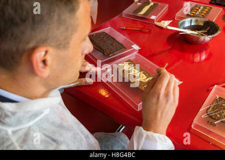 Junge kaukasischen männlichen Besucher macht seine eigene Tafel Schokolade bei Chocolat Frey Schokoladenfabrik und Museum in der Schweiz. Stockfoto
