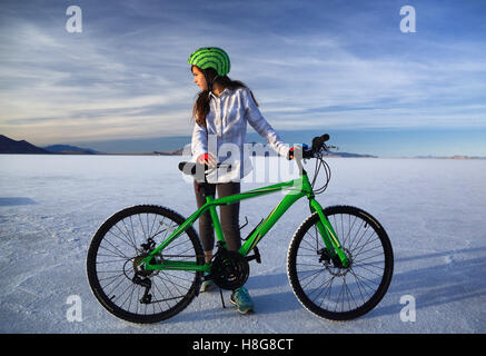 Eine Tween-Mädchen mit Wassermelone Fahrradsturzhelm streckt Lime green Mountainbike auf dem Salzsee von Bonneville in Utah. Stockfoto
