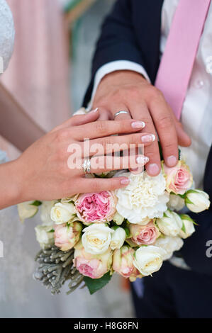 Hand der Braut und des Bräutigams mit Ringe für Hochzeit bouquet Stockfoto