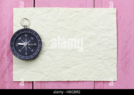 Kompass und Hinweis Papier auf dem rosa Holzboden, Konzept der Reisen und trekking. Stockfoto