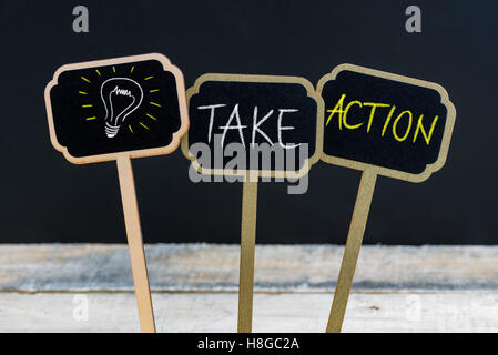 Konzept-Nachricht TAKE ACTION und Glühbirne als Symbol für die Idee, die auf hölzernen Mini Tafel Etiketten mit Kreide geschrieben Stockfoto