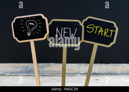 Konzept-Nachricht Neubeginn und Glühbirne als Symbol für die Idee, die auf hölzernen Mini Tafel Etiketten mit Kreide geschrieben Stockfoto