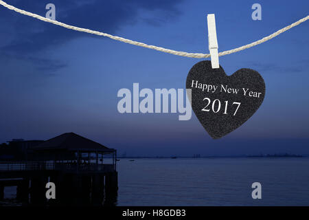 Black Heart auf Hanfseil auf Sonnenaufgang Hintergrund aufgehängt und frohes neues Jahr 2017 Text haben. Stockfoto