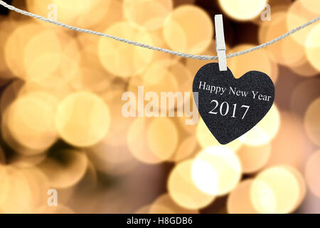 Black Heart auf Hanfseil auf Bokeh eine goldene Farbe Hintergrund aufgehängt und haben weiße Textfarbe frohes neues Jahr 2017. Stockfoto
