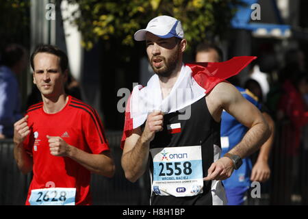 Athen, Griechenland. 13. November 2016. Ein Läufer ist eingehüllt in eine polnische Flagge. Tausende von Menschen aus der ganzen Welt nahmen an 2016 Athen Marathon authentisch, die in der Stadt von Marathon beginnt und endet in Athen, die Route, die der Legende nach zuerst von den griechischen Boten Pheidippides 490 v. Chr. betrieben wurde. Stockfoto