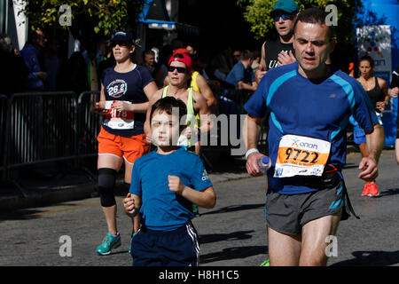 Athen, Griechenland. 13. November 2016. Ein Vater läuft mit seinem Sohn in Athen Marathon. Tausende von Menschen aus der ganzen Welt nahmen an 2016 Athen Marathon authentisch, die in der Stadt von Marathon beginnt und endet in Athen, die Route, die der Legende nach zuerst von den griechischen Boten Pheidippides 490 v. Chr. betrieben wurde. Stockfoto