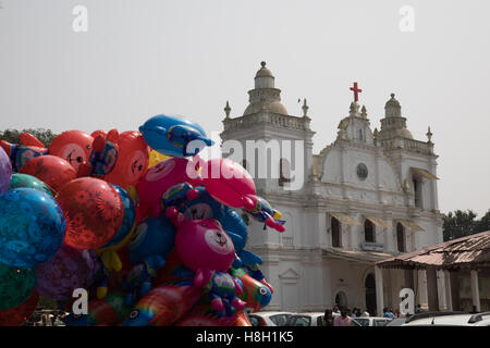 Varca, Goa, Indien. Sonntag, 13. November 2016. Katholische Gläubige feiern das Fest der Kirche Lady of Glory am Varca, in Goa, Indien. Mehrfarbige aufblasbare Spielzeuge und Luftballons n Vordergrund. Spielzeug Verkäufer zeigen ihre waren auf dem Gelände der Kirche. Stockfoto
