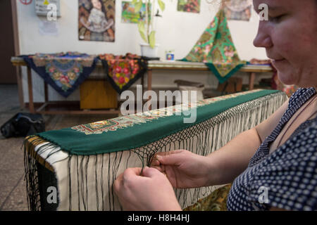 Eine Frau strickt manuell Knötchen auf einem traditionellen Pavloposadsky Schal in einer Textilfabrik in der Region Moskau, Russland Stockfoto