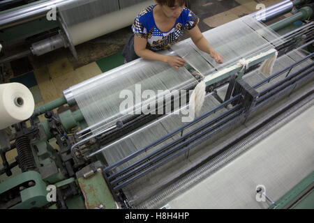 Ein Mitarbeiter des Unternehmens betreibt in einer Textilfabrik in Russland eine Maschine zur Herstellung von Textilien Stockfoto