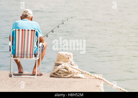 Fischer Angeln auf Dock im Sommer Stockfoto