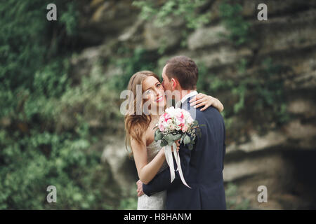 Frisch verheiratete Hochzeitspaar posiert und Braut hält in Händen Strauß Stockfoto