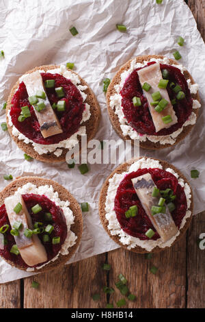 Kleine Sandwiches mit Hering, rote Beete und Frischkäse auf dem Tisch. vertikale Ansicht von oben Stockfoto