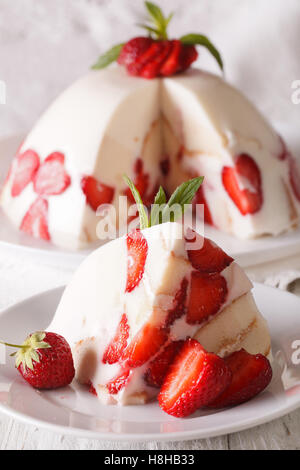 Käsekuchen mit frischen Erdbeeren und Biskuit Makro auf einem Teller. vertikale Stockfoto