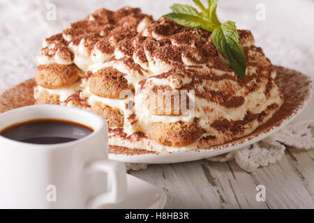 Italienisches Tiramisu-Kuchen auf einen Teller und Tasse schwarzen Kaffee auf den Tisch-Nahaufnahme. Horizontale Stockfoto