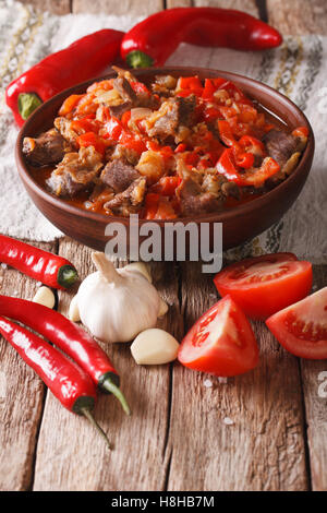 Lamm-Eintopf mit Zwiebeln, Tomaten und Pfeffer in einer Schüssel Großaufnahme auf dem Tisch. vertikale Stockfoto