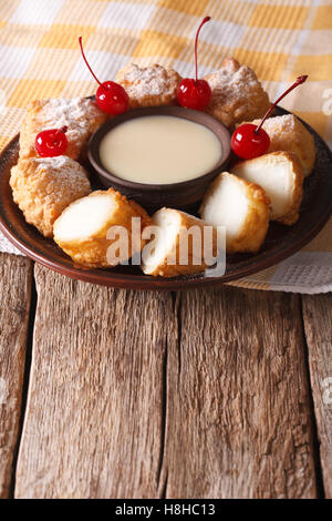 Dessert-Leche Frita mit Kondensmilch und Kirschen auf einer Platte-Nahaufnahme. Vertikal Stockfoto