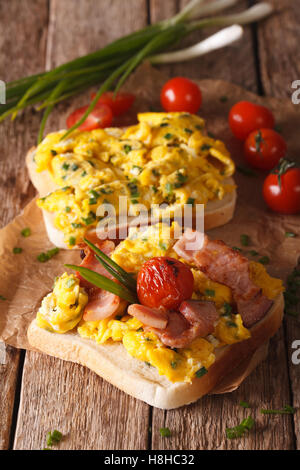 Hausgemachte Sandwich mit Rührei Eiern, Speck und Tomaten Nahaufnahme auf dem Tisch. Vertikal Stockfoto