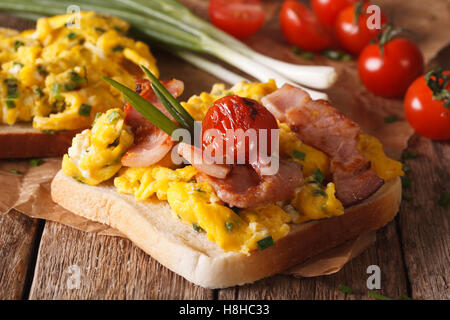 Sandwich mit Rührei, Speck, Frühlingszwiebeln und Tomaten-close-up auf dem Tisch. horizontale Stockfoto