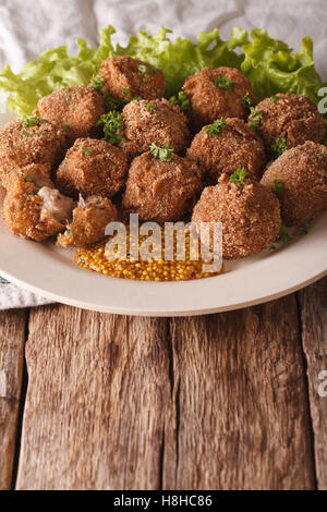 Holländische Fleischkroketten Bitterballen und Senf hautnah auf einem Teller auf den Tisch. vertikale Stockfoto