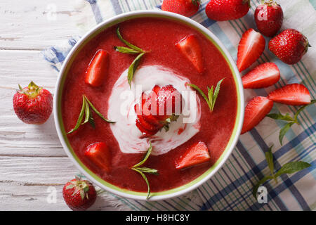 Köstliche Erdbeer-Suppe mit Sahne und Minze in einer Schüssel-Nahaufnahme. vertikale Ansicht von oben Stockfoto