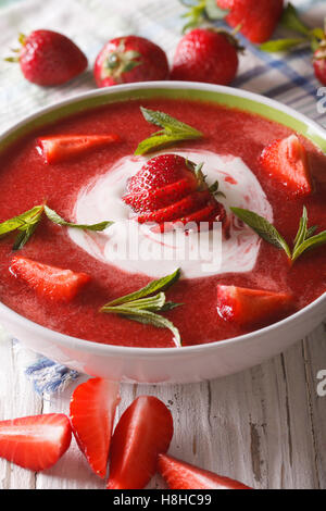 Süße kalte Erdbeer-Suppe mit Minze und saure Sahne in eine Schüssel Nahaufnahme. Vertikal Stockfoto