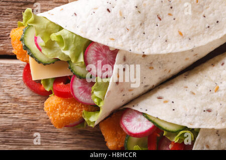 Burrito mit Fischstäbchen und Gemüse Makro auf dem Tisch. horizontale Ansicht von oben Stockfoto