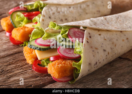 Burrito mit Fischstäbchen und Gemüse Makro auf dem Tisch. horizontale Stockfoto