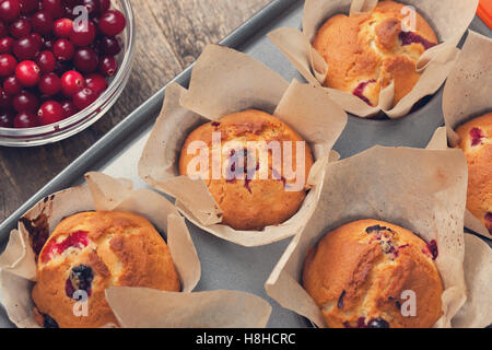 Muffins mit Preiselbeeren, Schüssel Preiselbeeren im Glas auf den alten hölzernen Hintergrund Stockfoto