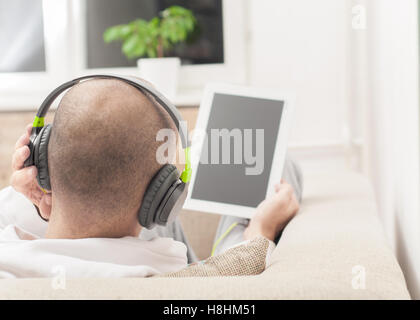 Junger Mann mit Tablet-pc zu Hause tragen von Kopfhörern Stockfoto