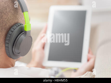 Junger Mann mit Tablet-pc zu Hause tragen von Kopfhörern Stockfoto