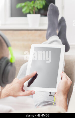 Junger Mann mit Tablet-pc zu Hause tragen von Kopfhörern Stockfoto