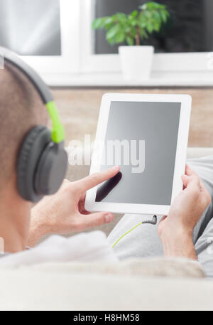 Junger Mann mit Tablet-pc zu Hause tragen von Kopfhörern Stockfoto