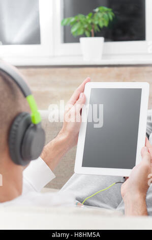 Junger Mann mit Tablet-pc zu Hause tragen von Kopfhörern Stockfoto