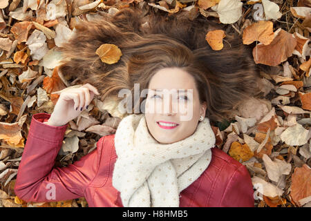 Junge Frau liegt auf gefallenen Herbst Blätter Porträt Stockfoto