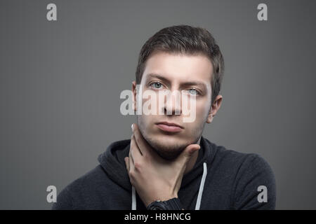 Stimmungsvolle Porträt von Ernst unrasiert Jüngling mit Hand unter Kinn Blick in die Kamera Stockfoto