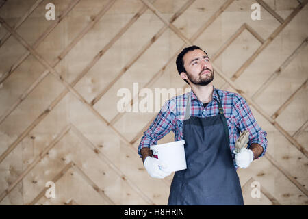 Mann mit Dose mit Farbe und Pinsel auf einer Holzwand Hintergrund nachschlagen Stockfoto