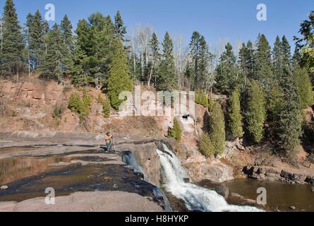 Ein Mann, die Fotos im stehen an der Spitze eines Wasserfalls im Stachelbeere Falls State Park in Two Harbors, Minnesota, USA. Stockfoto