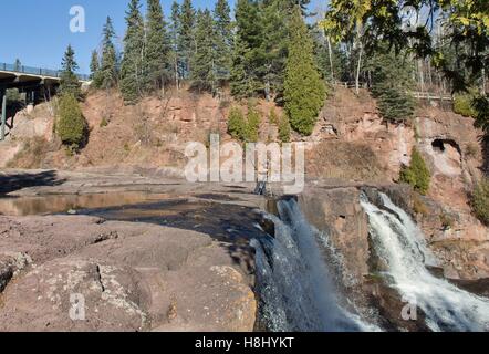 Ein Mann, die Fotos im stehen an der Spitze eines Wasserfalls im Stachelbeere Falls State Park in Two Harbors, Minnesota, USA. Stockfoto